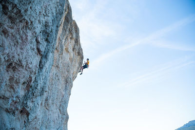 Low angle view of person on rock against sky