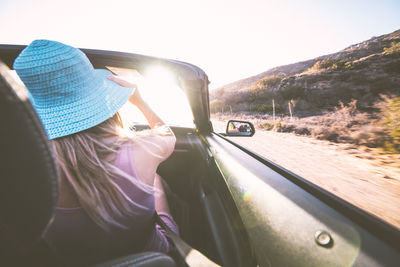 Rear view of woman in car against sky