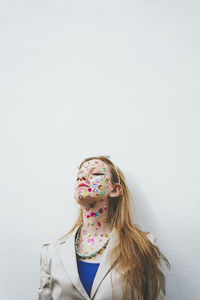 Woman with colorful stickers standing eyes closed leaning on white background