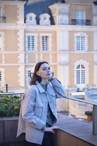 Portrait of young woman standing against built structures