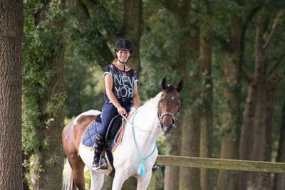 Portrait of woman riding horse against trees