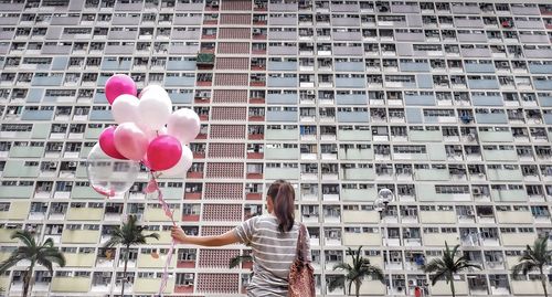 Rear view of woman with umbrella against buildings