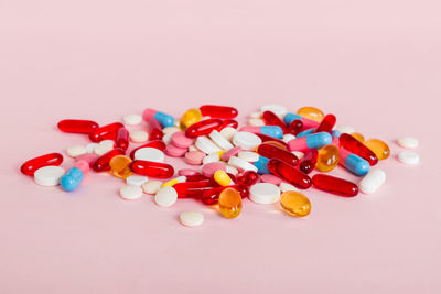 Pills spilling from bottle against pink background