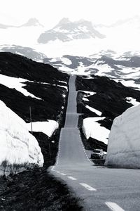 Road amidst snowcapped mountains against sky