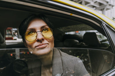 Contemplating businesswoman wearing yellow sunglasses sitting in car