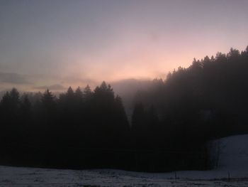 Scenic view of snow covered landscape against sky at sunset