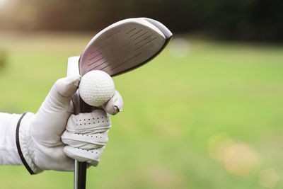 Cropped hand holding golf ball and club