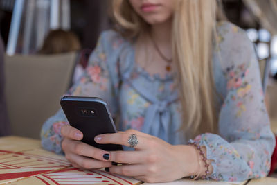 Midsection of young woman using mobile phone at restaurant