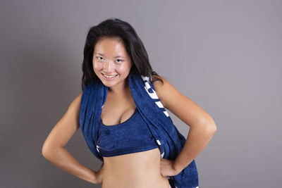 Portrait of young woman standing against gray background