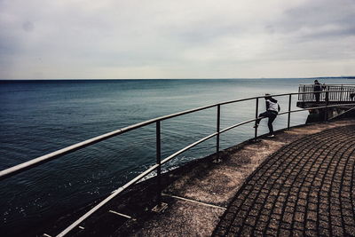 Pier on sea against cloudy sky