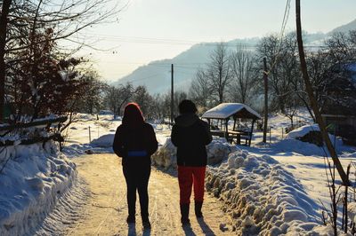 Rear view of women walking on snow covered landscape