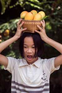 Girl carrying mango fruits with basket on head at farm