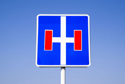 Close-up of road sign against clear blue sky