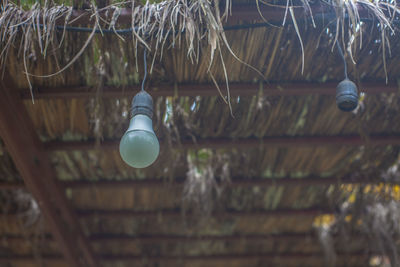 Low angle view of illuminated light bulb hanging from ceiling