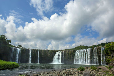 Scenic view of waterfall against cloudy sky