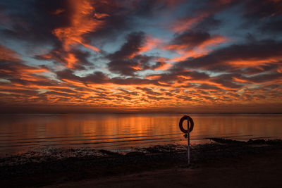 Scenic view of sea against dramatic sky during sunset