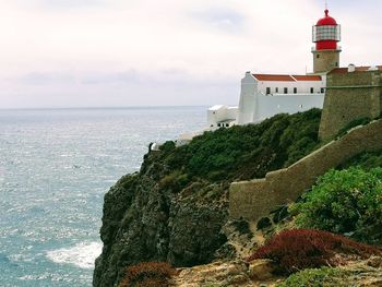 Lighthouse on beach against sky