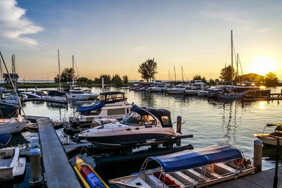 Boats moored at harbor against sky during sunset