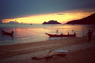 Boats in sea at sunset