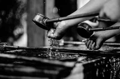 Cropped hands holding bamboo dippers at shishi-odoshi