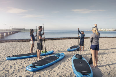 Male instructor training man and women at beach during sunset