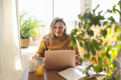 Smiling mature woman using laptop at cafe