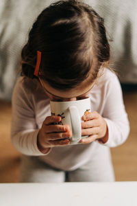 Portrait of cute girl drinking milk while sitting at home