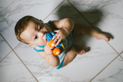 High angle view of baby boy holding toy on floor at home