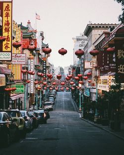 Lanterns over road in city against clear sky