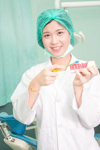 Portrait of smiling dentist brushing dentures