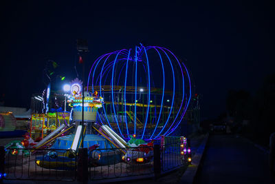 Illuminated ferris wheel against sky at night