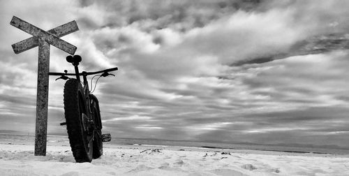 Road sign on snow field against sky