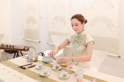 Young woman looking down while sitting on table