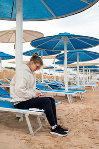 Young woman artist painting or doing travel sketches using watercolor by the seaside