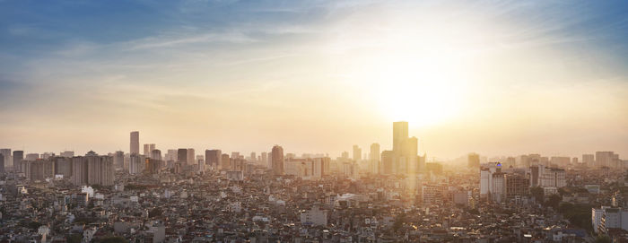 Aerial view of modern buildings in city against sky during sunset