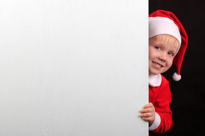 Portrait of cute girl standing against white wall