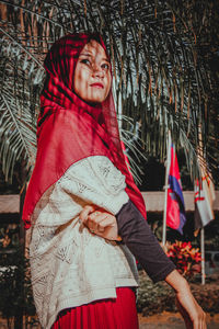 Side view of thoughtful young woman wearing hijab standing by tree
