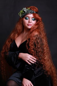 Sensuous young woman wearing wreath against black background