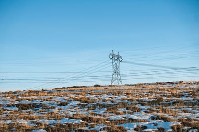 Aerial view of electricity pylons against clear sky during winter