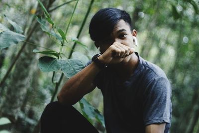 Portrait of young man sitting at forest