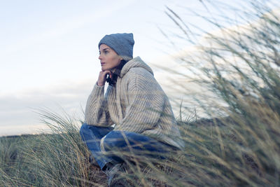 Woman outside in knitwear sitting and thinking. alone concept.