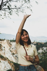 Portrait of smiling young woman standing against sky