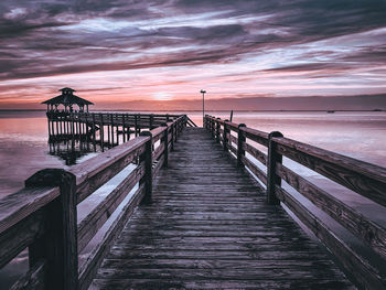 Pier over sea against sky during sunset