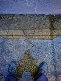 Low section of man standing on puddle