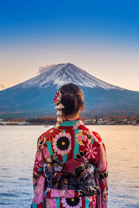 Rear view of woman standing by lake