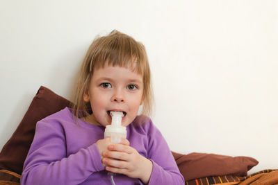 Sick child lies in bed and makes inhalation using a nebulizer.