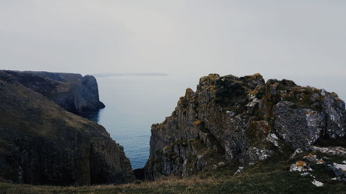 Scenic view of sea and cliff against clear sky