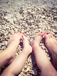 Low section of mother with baby girl at beach