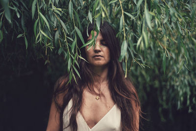 Young woman standing against tree