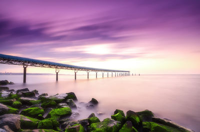 Low angle view of pier over sea at sunset